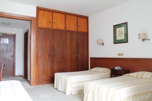 a hotel room with two beds and a closet at Residencial Greco in Funchal