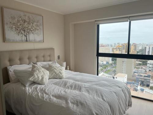 a bedroom with a white bed with a large window at Aparment Deluxe San Isidro in Lima