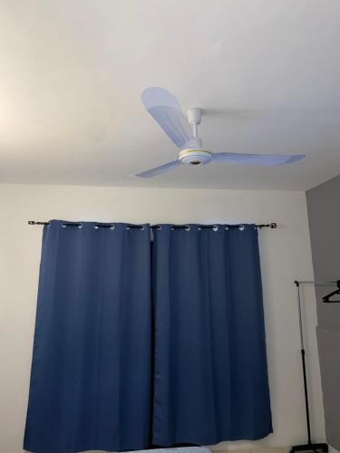 a ceiling fan in a room with a blue shower curtain at Katila-Rooms in Santa Maria