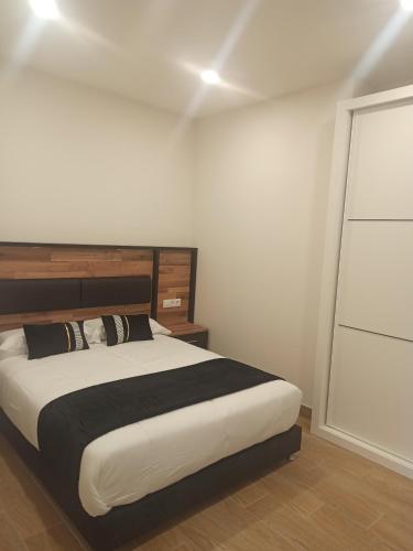 1 dormitorio con cama y pared blanca en Apartamentos Silgar Plaza, en Sanxenxo