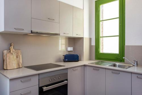 una cocina con armarios blancos y una ventana verde en Stay U-nique Apartments Fira BCN III, en Hospitalet de Llobregat
