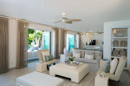 a living room with white furniture and a ceiling fan at FOOTPRINTS by DC in Saint James