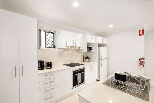 a white kitchen with white cabinets and appliances at Air-Con, Netflix, Close to Transport & Private in Brisbane