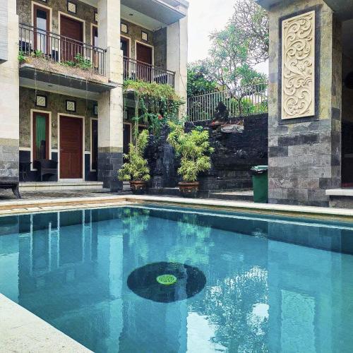 a swimming pool in front of a building at Santhi Graha by NauliTabitha in Legian