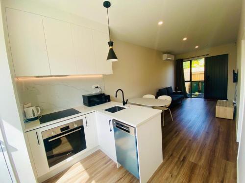 a kitchen with white cabinets and a living room at Holiday / Short term Rent in Auckland