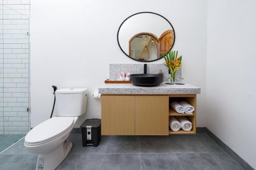 a bathroom with a toilet and a mirror at Villa Greenland Canggu by Nagisa Bali in Dalung