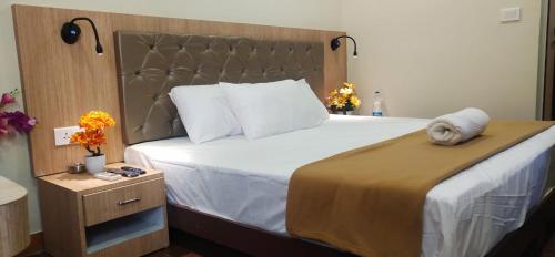 1 dormitorio con 1 cama grande y cabecero de madera en Hotel Amutham, en Tiruchchirāppalli