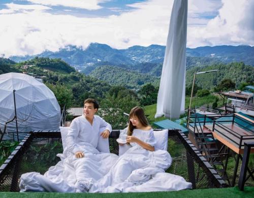 a man and a woman sitting on a balcony with a drink at ภูตะวัน-บ้านท่าจัน ม่อนแจ่ม in Mon Jam