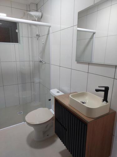 a bathroom with a sink and a toilet and a mirror at Apartamento belvedere do lago in Serra Negra