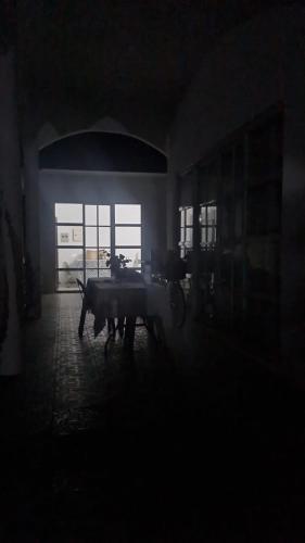 ein dunkles Zimmer mit einem Tisch und einem Fenster in der Unterkunft Palapag White House, your holiday home in Palapag
