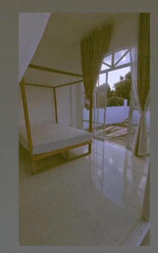 Bett in einem Zimmer mit einem großen Fenster in der Unterkunft Palapag White House, your holiday home in Palapag