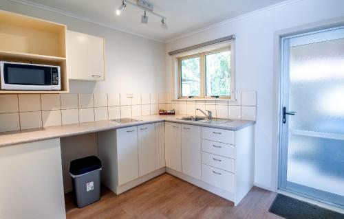 a white kitchen with a sink and a microwave at Ripple Rotorua in Rotorua