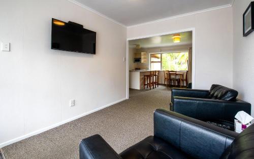 a living room with couches and a television on a wall at Ripple Rotorua in Rotorua