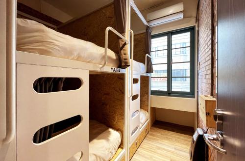 two bunk beds in a room with a window at Funtime Hostel in Chiayi City