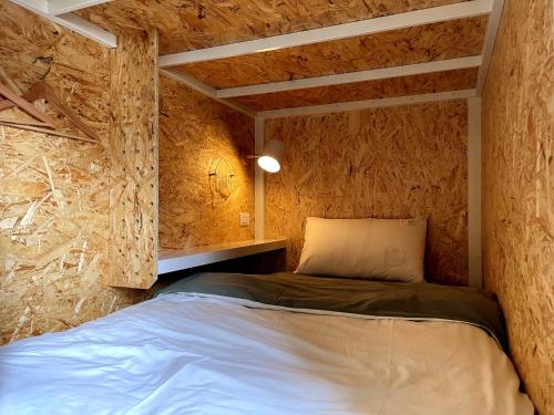 1 dormitorio con 1 cama en una habitación con paredes de madera en Funtime Hostel, en Chiayi