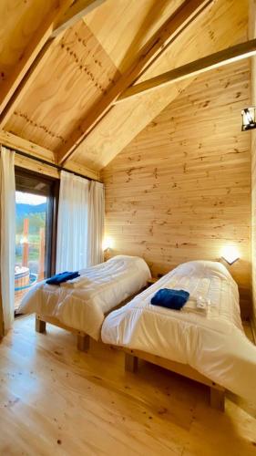 a bedroom with two beds in a wooden room at Casa Huilo in Neltume