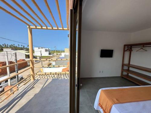 a bedroom with a bed and a balcony with a view at Casa Tapera - Porto de Pedras/AL in Pôrto de Pedras