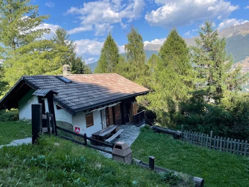 a small house on a hill with a fence at Chalet typique tout confort avec studio en dessous in Hérémence