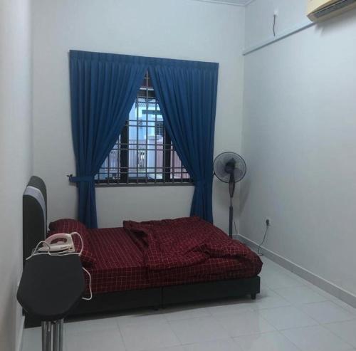 1 dormitorio con 1 cama con cortina azul y ventana en The Hanraz home stay en Kota Tinggi
