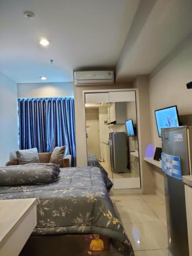 a room with a bed and a couch and a mirror at Grand Kamala Lagoon Bekasi Apartement - Type Studio in Pulosirih