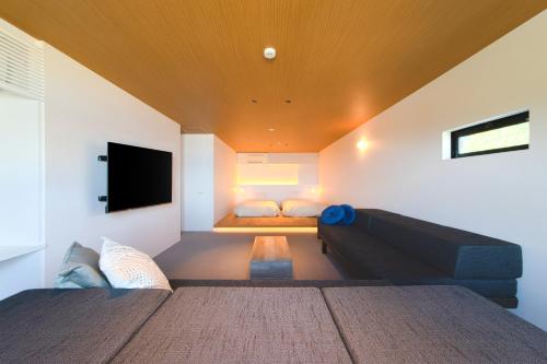 a living room with a couch and a tv at セトノウツツ in Suo Oshima