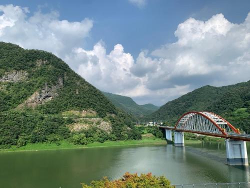 a bridge over a river with mountains in the background at Danyang Rio 127 Guesthouse River View in Danyang