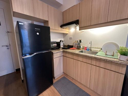 a kitchen with a black refrigerator and a sink at CELANDINE Residence by DMCI in Manila