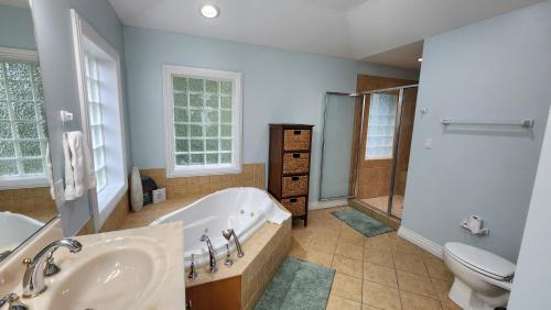 a bathroom with a tub and a toilet and a sink at No Fee Luxury Pet Friendly 7BR Soundfront retreat with Elevator, Heated Pool and Hot Tub in Kitty Hawk