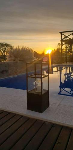 a glass box sitting next to a pool with the sunset at Cristino Multiespacio in Goya