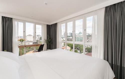 a bedroom with a white bed and a large window at M Village Hai Bà Trưng in Ho Chi Minh City