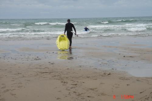 a man walking on the beach with a yellow surfboard at Sea Jade Guest House in Bude