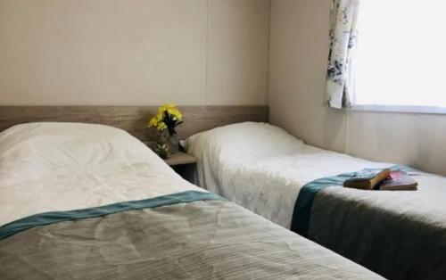 a room with two beds and a vase of flowers at Greenhouse 24 in Little Clacton