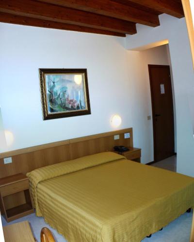 a bedroom with a bed and a painting on the wall at Hotel Tiziana Garnì in Gargnano