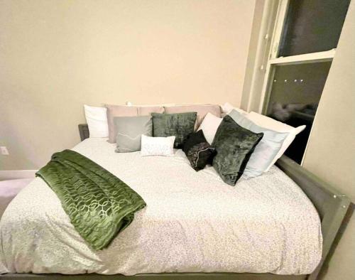 a bed with green and white pillows and a window at Luxury 2-Bed 2 Bath Apartment in King of Prussia
