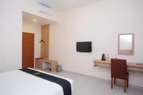 um quarto com uma cama, uma secretária e uma televisão em Urbanview Hotel DJ Inn Tegal em Tegal