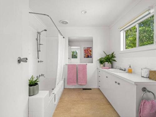 ein weißes Bad mit einem Waschbecken und einer Dusche in der Unterkunft Elm Cottage in Benalla