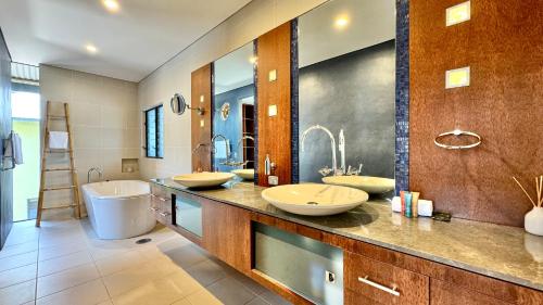 a bathroom with two sinks and a tub and a toilet at Allawah Port Douglas in Port Douglas