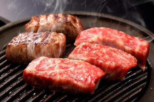four pieces of meat cooking on a grill at Kami no yama Azumaya in Kaminoyama