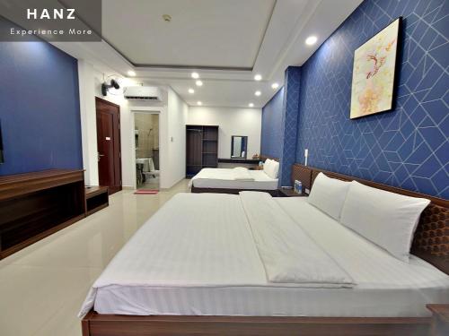 - une chambre avec 2 lits et un mur bleu dans l'établissement HANZ Hung Phu Hotel, à Hô-Chi-Minh-Ville