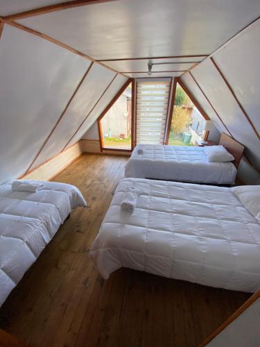 a room with three beds in a tent at Cabañas kavizke in Puerto Puyuhuapi
