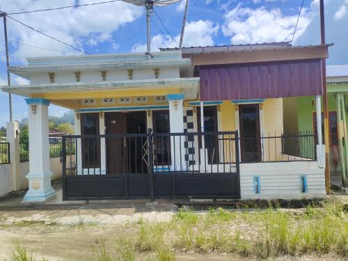 mały żółty dom z balkonem na ulicy w obiekcie Pematang Siantar Vacation House w mieście Pematangsiantar