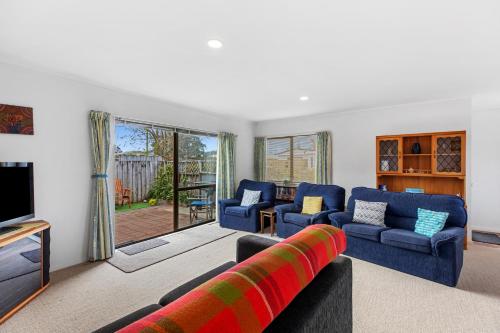 a living room with two blue couches and a television at Riviera Casa - Mount Maunganui Holiday Home in Mount Maunganui