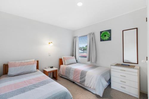 a bedroom with two beds and a dresser and a window at Riviera Casa - Mount Maunganui Holiday Home in Mount Maunganui