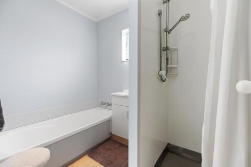 a white bathroom with a tub and a sink at Riviera Casa - Mount Maunganui Holiday Home in Mount Maunganui