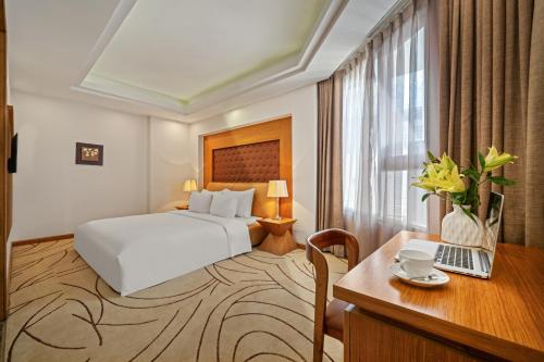 a hotel room with a bed and a desk with a laptop at Diamond Sea Hotel in Da Nang
