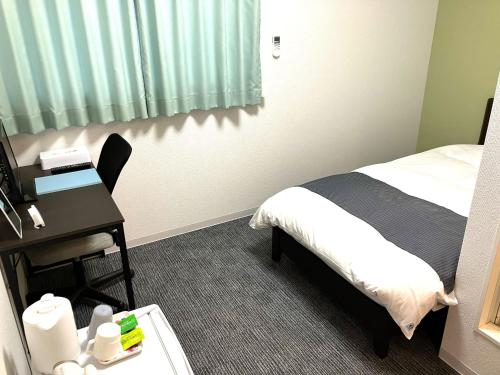 um quarto de hotel com uma cama e uma secretária com uma secretária em IMAS Village Court Rokkokuodaka em Minamisouma