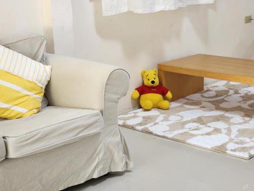 a yellow teddy bear sitting on the floor next to a chair at HOMEis Villa Sattahip in Ban Tao Than