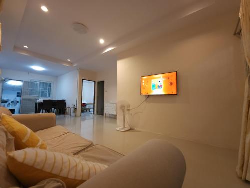 a living room with a couch and a tv on the wall at HOMEis Villa Sattahip in Ban Tao Than