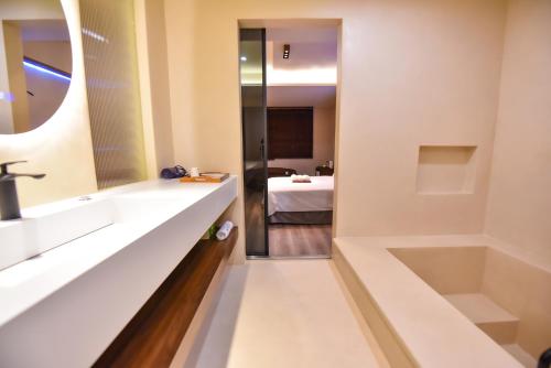 a bathroom with a sink and a tub and a bedroom at Two Couples Leisure Art Motel in Tainan