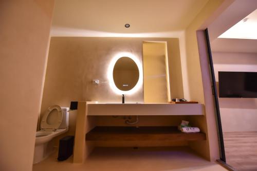 a bathroom with a sink and a mirror and a toilet at Two Couples Leisure Art Motel in Tainan
